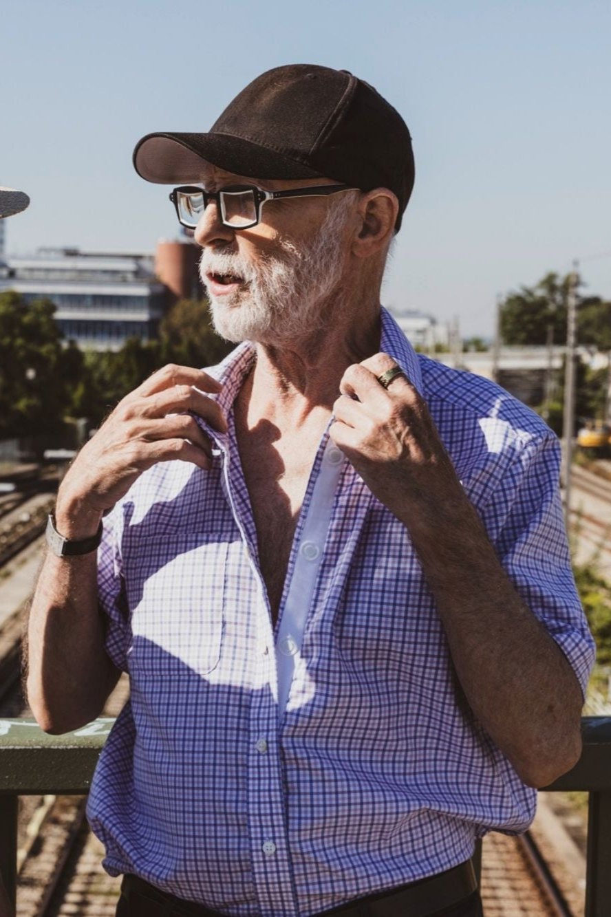 Ein Herr im karierten Magnethemd öffnet das hemd und zweigt die Magnetleiste. Ein weiterer Herr steht daneben im hellblauen Oxfordhemd mit Magnetverschluss.